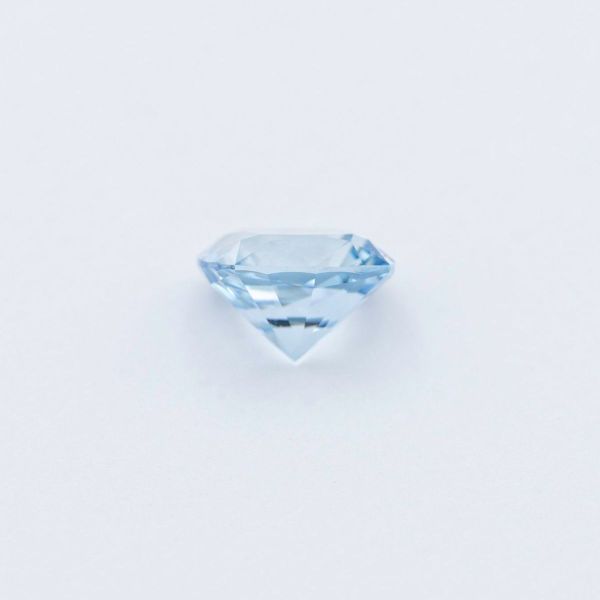 True-to-life photograph of a cushion cut aquamarine from the side.
