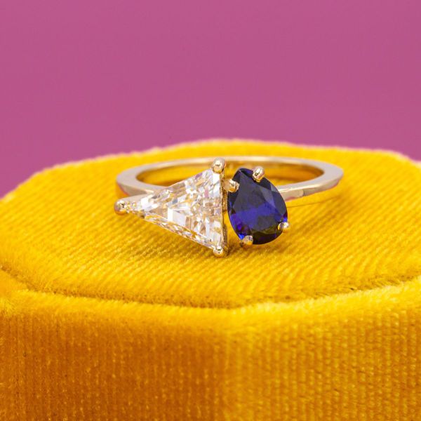 It’s a win for high contrast design in this toi et moi engagement ring. The light and airy lab-created diamond sets off the dark blue lab-created sapphire, and the fine lines of the trillion are softened by the curved pear. Both sit beautifully in yellow gold.