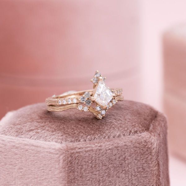 A moissanite center stone sits amid diamonds on this rose gold ring.