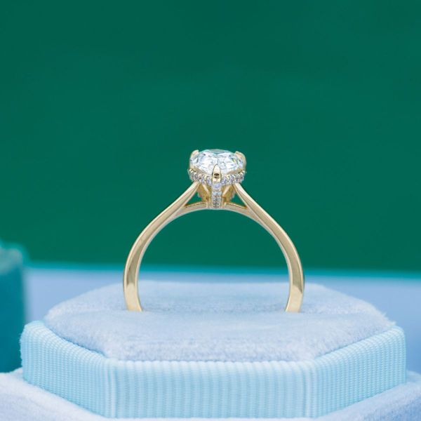 A hidden halo of diamond accent stones extends along the prongs in this pear cut diamond engagement ring.
