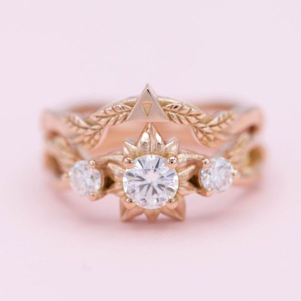 A Silent Princess flower inspired design surrounds the moissanite center stone of this Zelda inspired engagement ring.