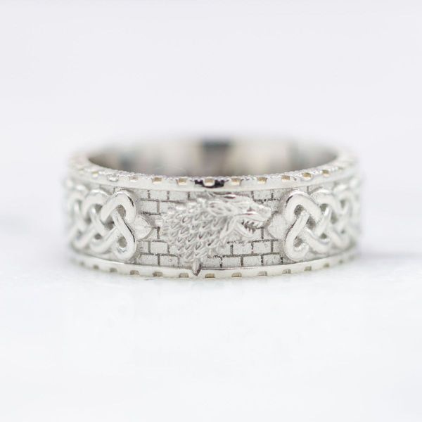 This platinum wedding band features a dire wolf inspired centerpiece with a brick background and Celtic sailor’s knots.