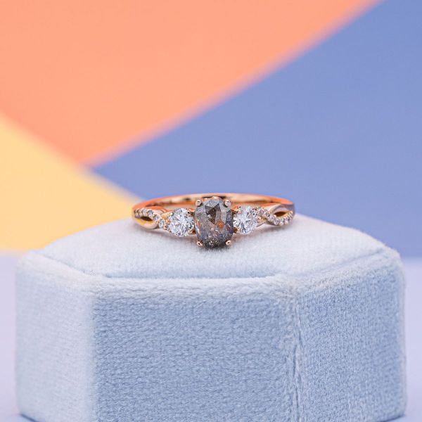 The salt and pepper diamond at the center of this engagement ring has slight tins of colors besides white and gray.