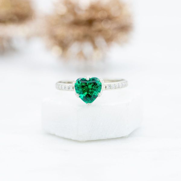 Our bride-to-be’s emerald heart sits secure in this engagement ring’s white gold lotus blossom setting on a diamond pavé band.