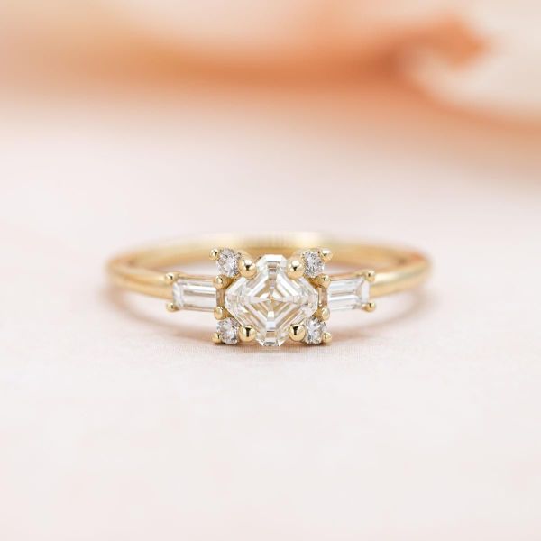 A natural asscher cut diamond makes up the center of this unique engagement ring.