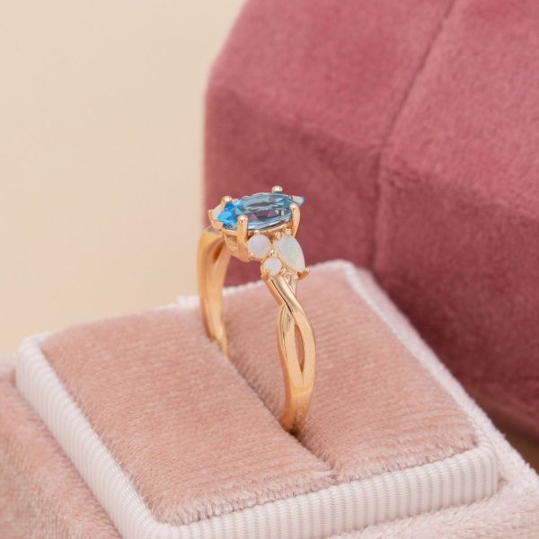 A Swiss blue topaz is surrounded by white opals in this winter inspired engagement ring.