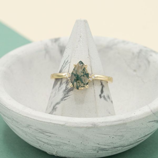A pear cut moss agate in a yellow gold setting.