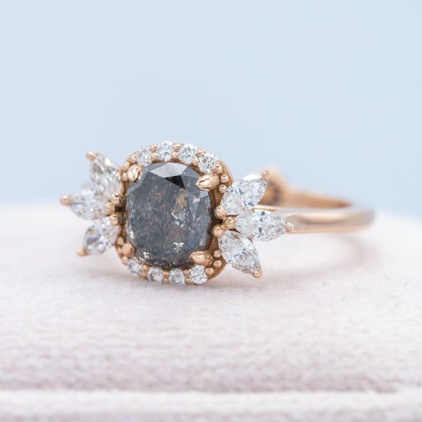 A salt and pepper cushion cut diamond is framed by a uniquely designed halo.