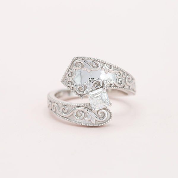一个大胆的订婚戒指设计，以横扫和复杂的细节曲线周围的asscher切割中心石。