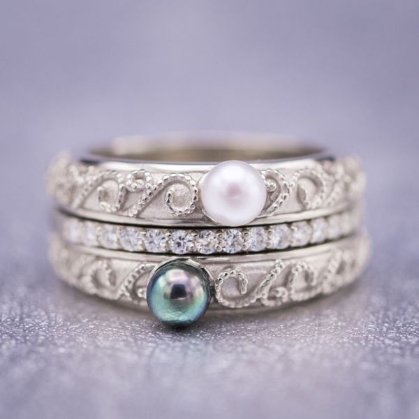 这三枚戒指复古灵感的新娘套装围绕着一枚精致的钻石永恒戒指，两枚戒指以黑白珍珠为特色。