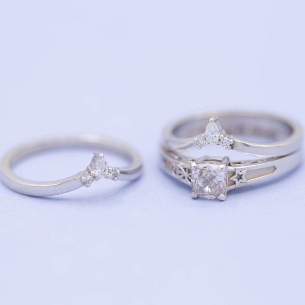 Two white gold tiara-shaped bands encompass a princess cut diamond on this anchor engagement ring.