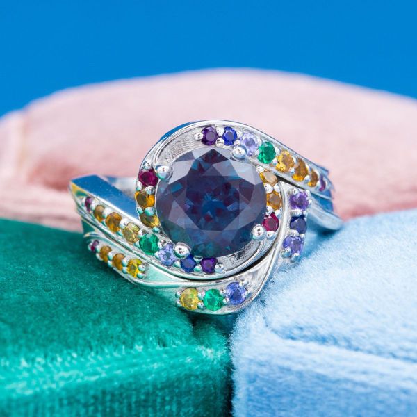 A rainbow of accent gems swirls around the center alexandrite in this engagement ring.