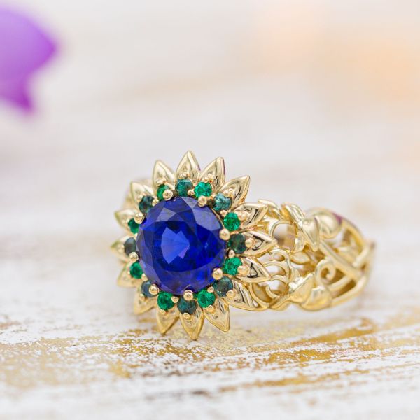 Sunflower engagement ring with sapphire, emerald and alexandrite and a buck and doe detail in the nature-inspired band.
