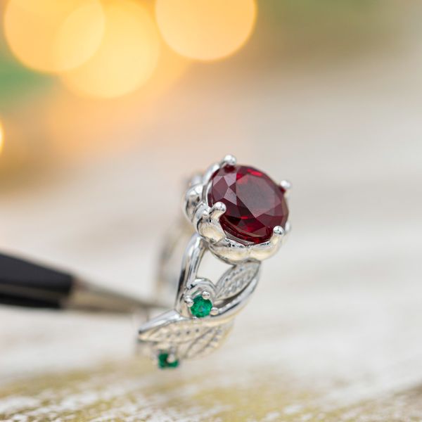 Rose ring with a lab-made ruby center stone and emerald accents in the leafy band.