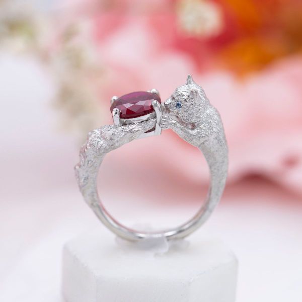 A playful kitten chases a lab created ruby around this engagement ring.