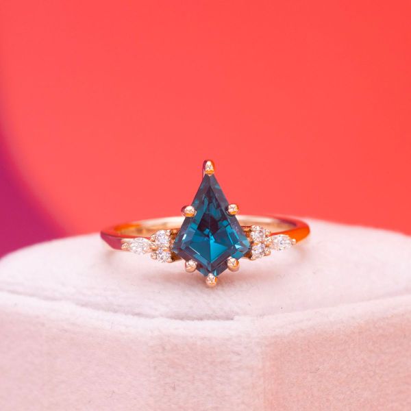 A blue kite cut alexandrite sits in yellow gold with diamond accents.