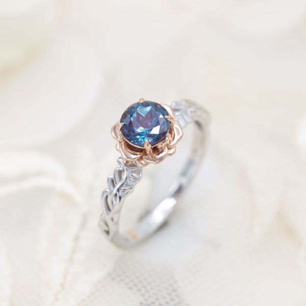 A vining white gold band frames the sculptural rose gold flower setting in this alexandrite engagement ring.