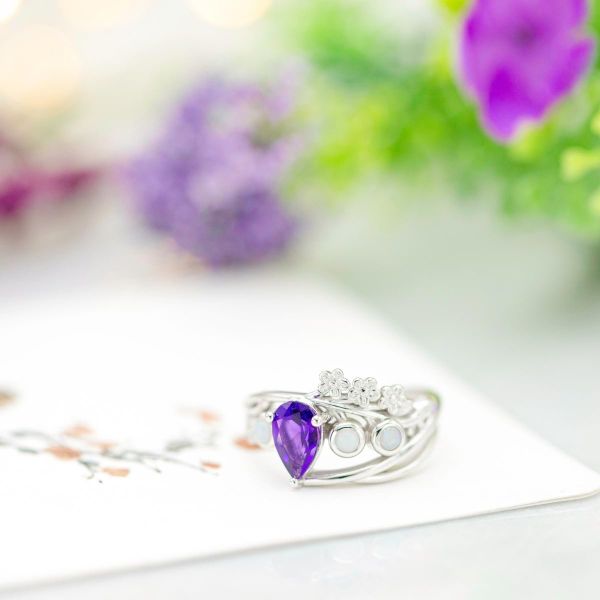 以花为灵感的订婚戒指，勿忘我花的蛋白石设计围绕着梨切紫水晶。