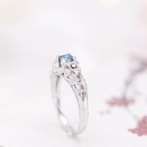 This teal blue diamond is paired with black and colorless diamond and white opal accents.
