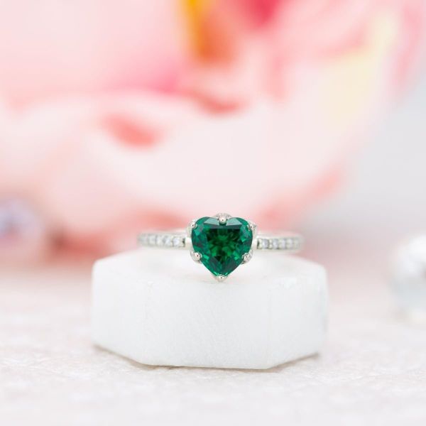 This heart shaped emerald sits in a lotus flower basket.