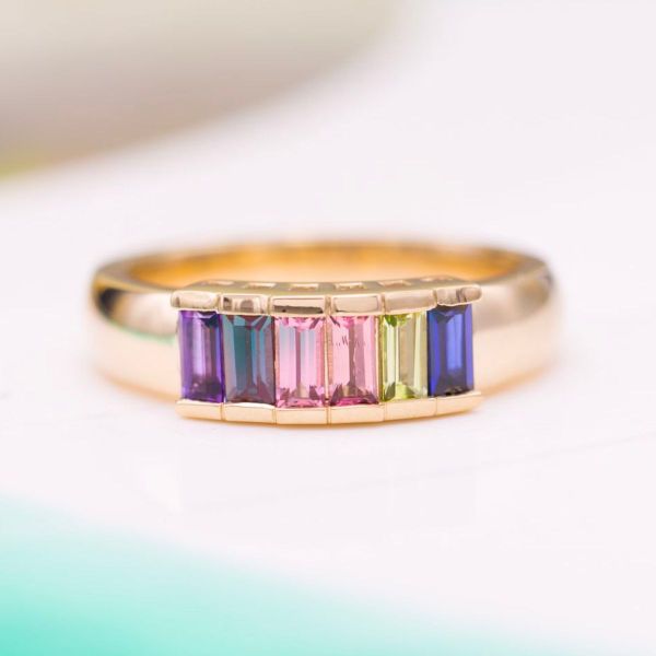 A rainbow of baguette cut gems grace this engagement ring: an amethyst, alexandrite, tourmaline, peridot, and two sapphires.