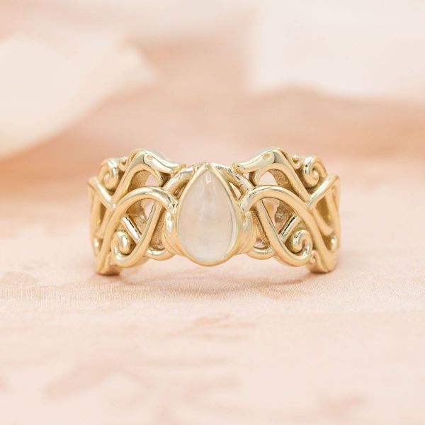 Elven inspiration runs wild in this his and hers bridal set and wedding band, featuring intertwining yellow gold metalwork and teardrop shaped moonstones.