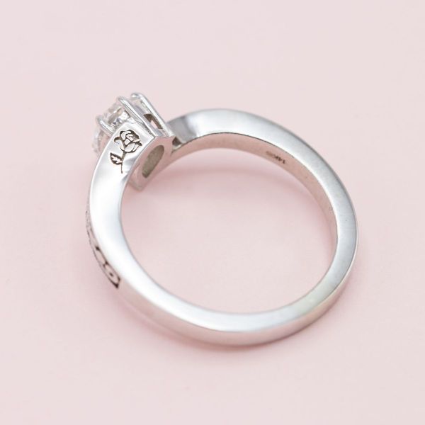 A peekaboo rose is engraved on the band’s profile of this diamond engagement ring.