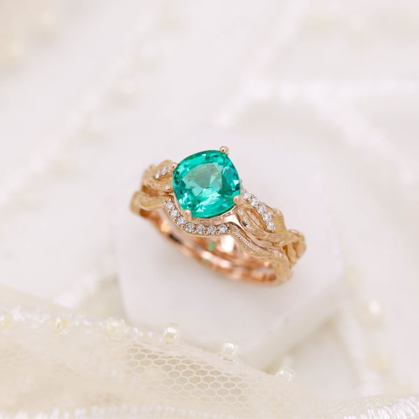 A yellow gold antique-style setting holds a natural emerald and pavé diamonds.