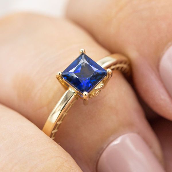 A simple yellow gold band allows the brilliance of this princess cut sapphire to speak for itself. We added subtle embellishments to the profile of the band, leaving the top down view clean and clear of distractions.