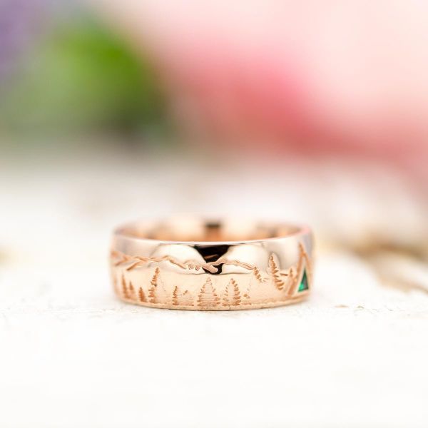 The minimalistic mountains on this rose gold wedding band are accentuated by a triangle emerald tree.