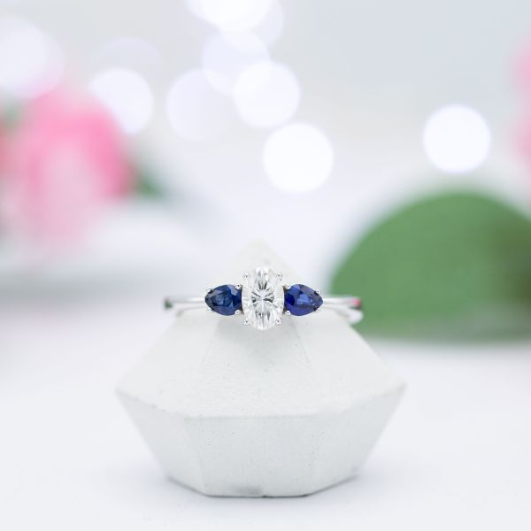 Two 0.2-carat pear-shaped sapphires flank the center stone, adding roughly $275 to the total. A pair of similarly-sized diamonds might be closer to $700 extra, while a topaz or amethyst pair might be closer to $100 extra.