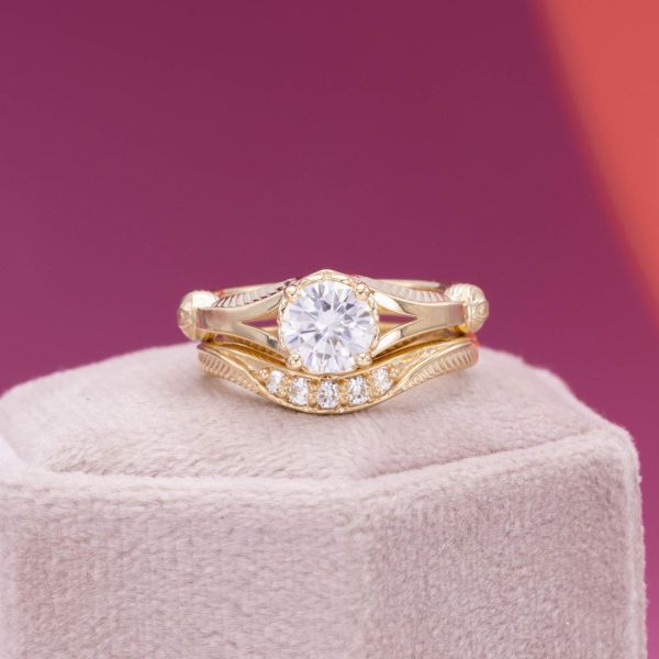 A sparkling round moissanite sits in a beautiful gold setting.