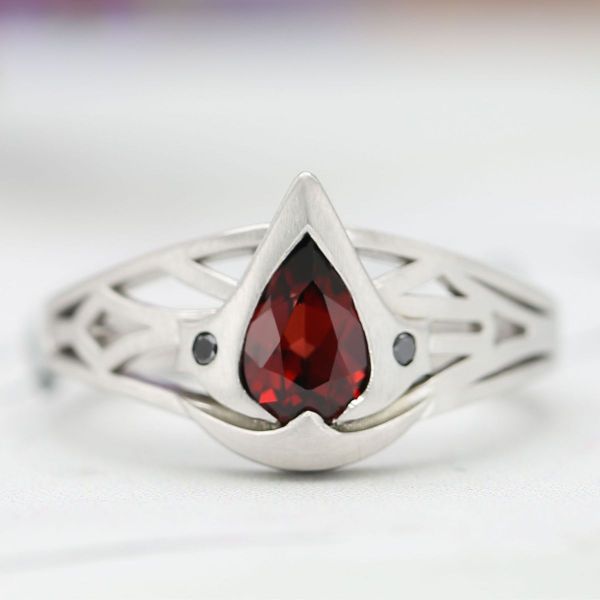 This Assassin’s Creed inspired engagement ring hides two hidden blades next to the garnet Mozambique center stone.
