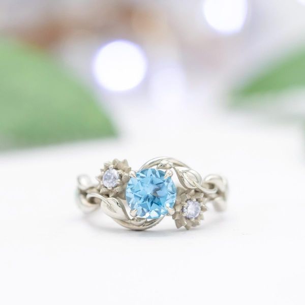 A Swiss blue topaz sits in the center of this lotus inspired ring.