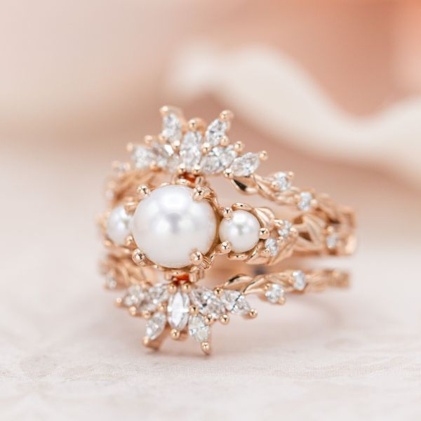 迷人的完美在这三枚戒指的新娘套装，周围的三颗珍珠设置与无尽的钻石闪闪发光。