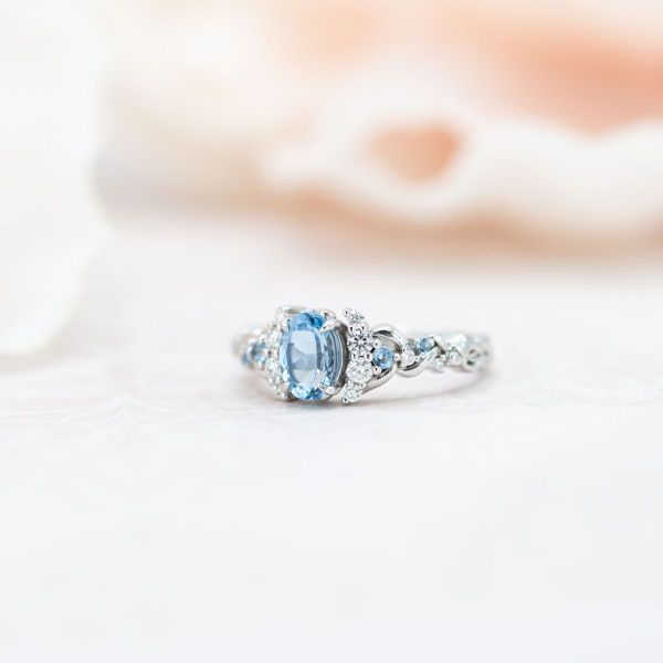 An oval aquamarine set in white gold with diamond and fellow aquamarine accents.