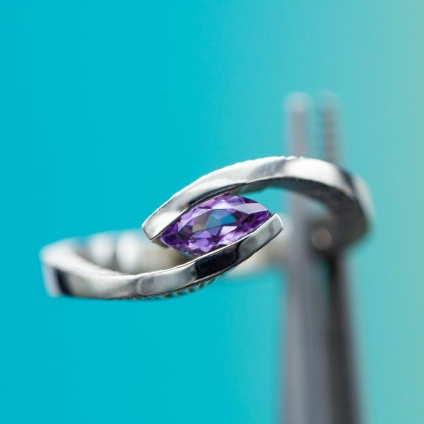 Imitating a tension setting, the bold sweeping arms of the bypass setting appear to suspend the marquise amethyst, which rests comfortably on a hidden gallery rail to ensure the gem will be secure for daily wear.