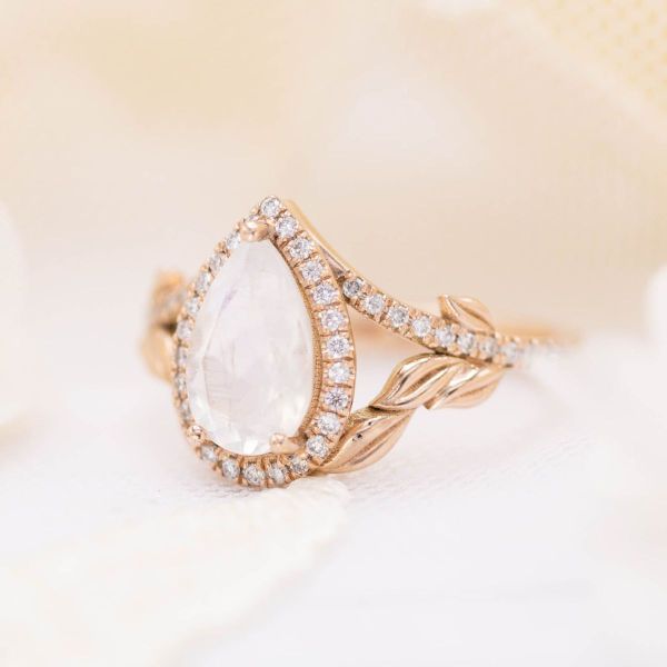 Leaves create the lower strands of the split-shank band in this moonstone and diamond engagement ring.
