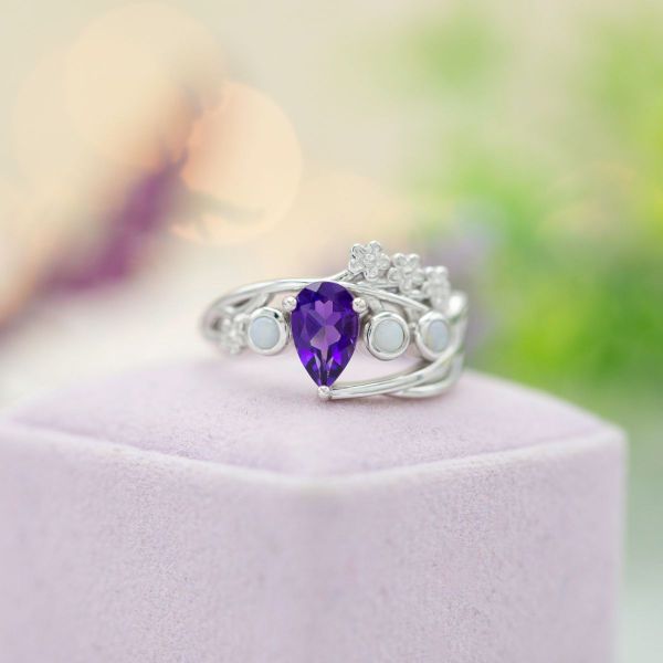White opals accent the pear cut amethyst in the center of this engagement ring.