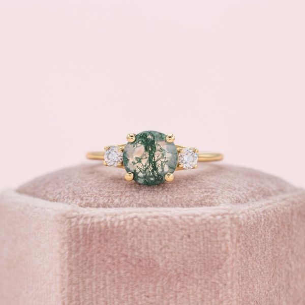 In this yellow gold ring, both sides of the moss agate center stone sport a diamond.