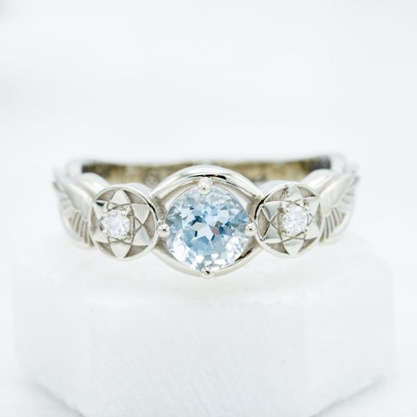 An aquamarine takes center stage next to sharingan eye-like detailing in this Naruto inspired engagement ring.