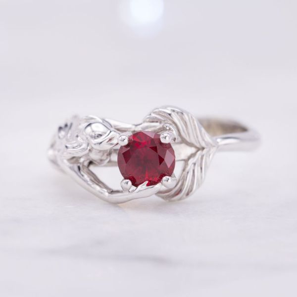 A whimsical mermaid setting in white gold cradling the lab-created ruby in her fins and hands.