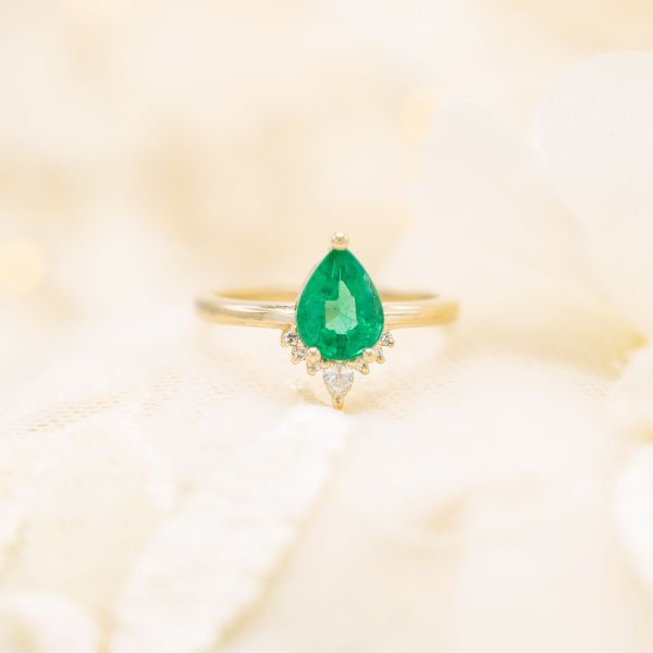 The pear emerald at the center of this engagement ring has yellow undertones.