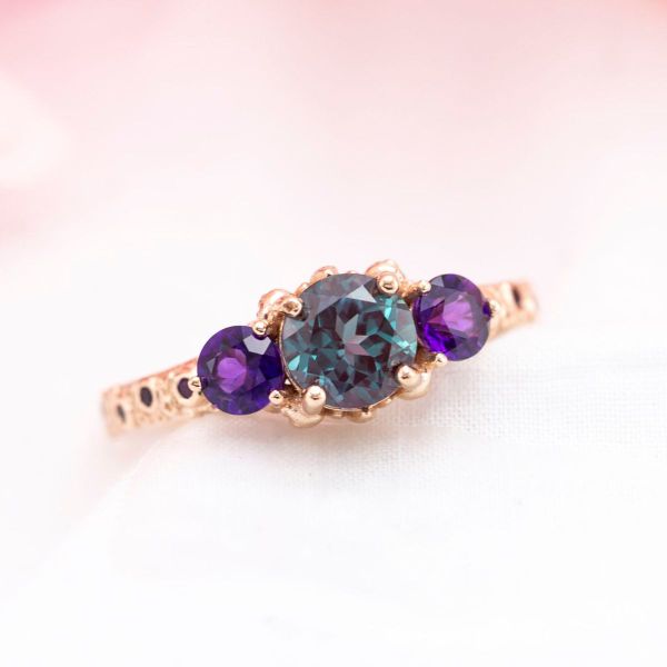 Amethyst side stones highlight the purple hues in the center alexandrite of this engagement ring.