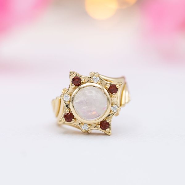 一枚独特的月光石订婚戒指，有石榴石和钻石组成的星状光环