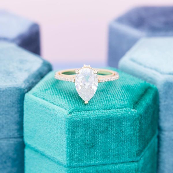 This bright white pear shaped moissanite sparkles brightly in this yellow gold engagement ring.