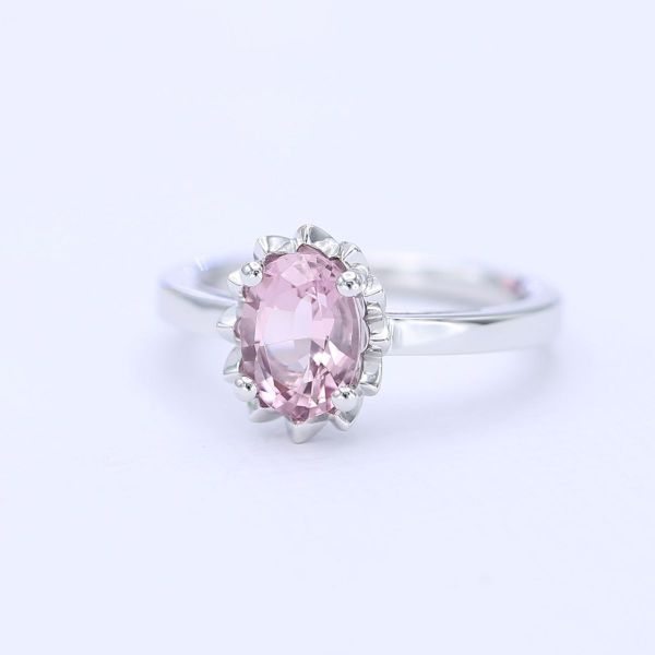 A light pink morganite blossoms from a white gold setting that resembles a flower in this solitaire engagement ring.