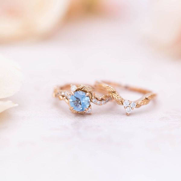 A round aquamarine sits in the center of this dainty floral bridal set.