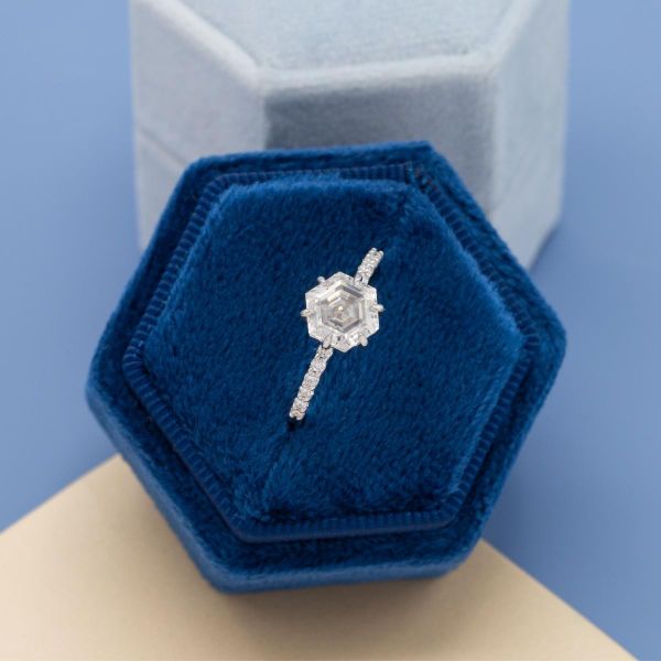 A hexagon shaped moissanite brings a modern taste to this pave engagement ring.