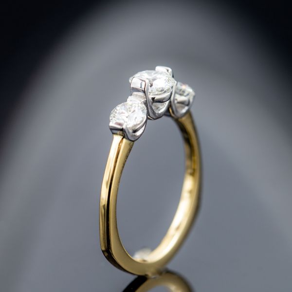 A three stone setting with three minimalist bar settings for the diamonds, paired with a gold euro shank.